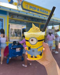 a hand holding up a yellow cup filled with ice cream and topped with a minion