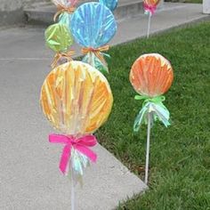 some colorful candy lollipops sitting in the grass on top of a sidewalk