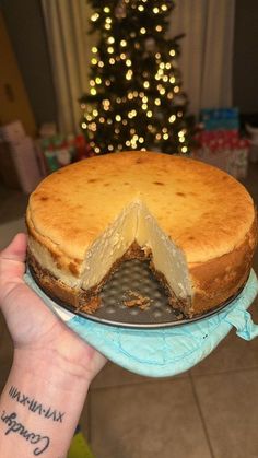 a person holding up a cake with a slice taken out of it on a plate