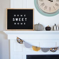 a mantle with a clock and some decorations on it next to a sign that says home sweet home