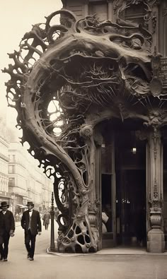 two men walking past a large sculpture on the sidewalk