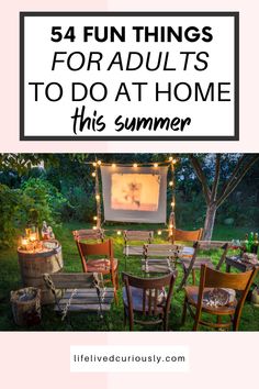 an outdoor movie party with chairs and lights on the grass, in front of a tv screen