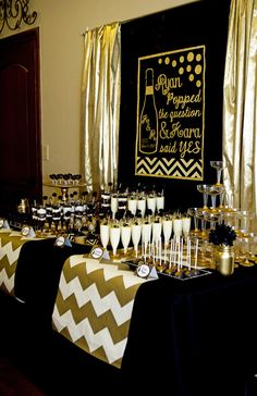 a table with champagne glasses and desserts on it in front of a black backdrop