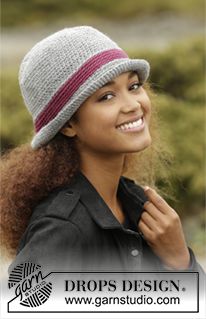 a woman wearing a gray and red hat with stripes on the brim is smiling