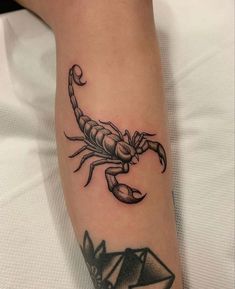 a scorpion tattoo on the leg of a person with an origami in front of it