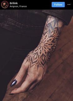 a woman's hand with an intricate tattoo design on her left arm and wrist