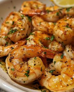 a white plate topped with cooked shrimp and lemon wedges