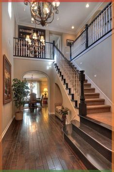 an entry way with stairs, chandelier and potted plant in the center