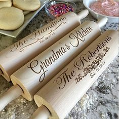 four wooden rolling pins with the names grandma's kitchen on them next to some cookies