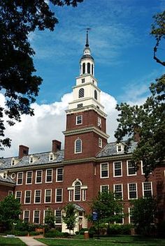 a tall brick building with a clock on the top and a steeple above it