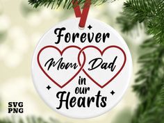 a white ornament with two hearts hanging from a tree branch that says, forever mom dad in our hearts