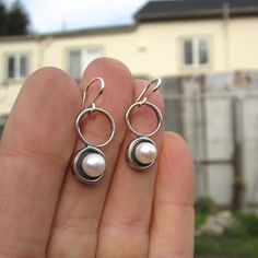 A minimal and modern look with a nod to old school pearl earrings. These sterling silver and pearl earrings are set in a modern round shadow bezel style and hang from sculptural open circles. The cultured pearl is half drilled on the bottom and glued to a sterling post soldered to the necklace for durability. You will get a lot of compliments when wearing this mini art piece. To see all my pearl jewelry go here: https://www.etsy.com/shop/marmarModern?ref=seller-platform-mcnav&section_id=1328 Modern Pearl Drop Earrings For Anniversary, Modern Round Sterling Silver Pearl Earrings, Silver Minimalist Pierced Pearl Earrings, Modern Round Pearl Earrings, Modern Everyday Dangle Pearl Earrings, Modern Dangle Pearl Earrings For Everyday, Modern Silver Pierced Pearl Earrings, Minimalist Round Pearl Drop Earrings, Modern Sterling Silver Pearl Earrings