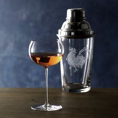 a glass of wine next to a decanter on a wooden table with a blue wall in the background