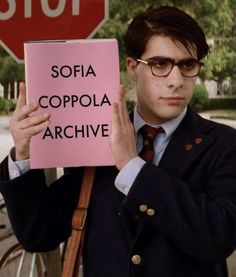 a man holding up a pink sign that says sofia coppola archive