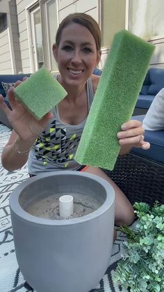 a woman sitting on a patio holding two sponges