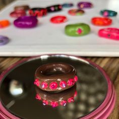 a chocolate donut sitting on top of a plate with pink and green decorations around it