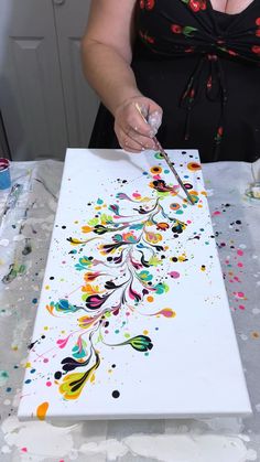 a woman is painting on a canvas with paint splattered all over the surface