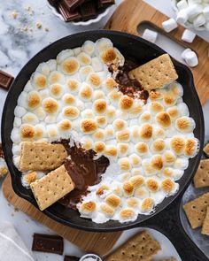 a skillet filled with marshmallows, chocolate sauce and graham crackers