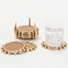 three pieces of gold colored metal with beading on them and a glass filled with water