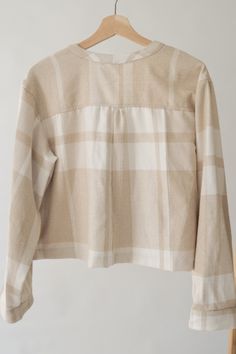 a white and beige checkered shirt hanging on a wooden hanger