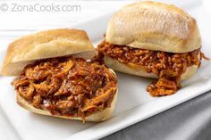 two pulled pork sandwiches sitting on top of a white plate