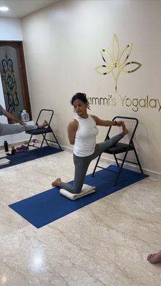 a woman standing on a yoga mat in front of a wall