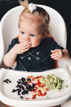 a baby sitting in a high chair eating food