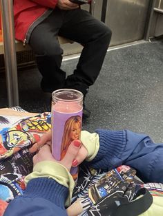 a person holding a cup with a pink liquid in it on the floor next to other people