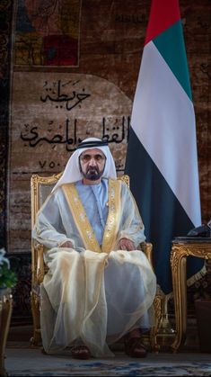 a man sitting in a chair next to two flags