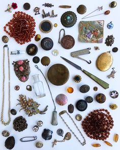 an assortment of jewelry is laid out on a white surface, including necklaces and brooches