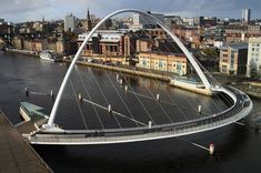 an aerial view of a bridge spanning the width of a river with buildings in the background