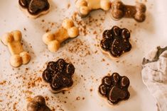 some dog treats are laying out on a white surface with brown and black frosting