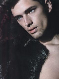 a shirtless man wearing a fur collar