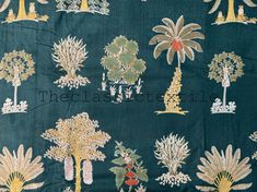 an embroidered fabric with trees and bushes on green, gold and white colors is shown