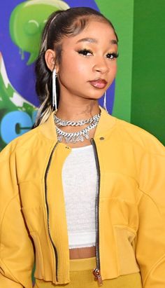 a woman in yellow jacket and skirt posing for the camera