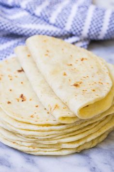 a stack of tortillas sitting on top of a white counter next to a blue towel