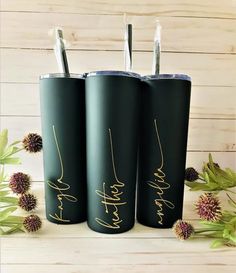 three black tumblers with gold writing on them and one has two straws in it