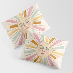 two decorative pillows with sun faces on them