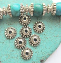 several beads are sitting on top of a turquoise plate