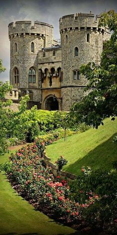 the castle is surrounded by lush green grass and flowers on either side of the walkway