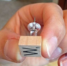 a person holding a tiny wooden block with the letter w on it