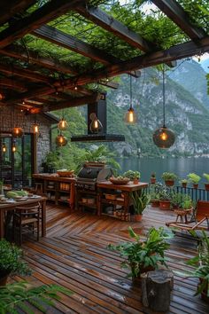 an outdoor kitchen with lights hanging from the ceiling and potted plants on the deck