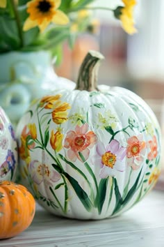 painted pumpkins and flowers are sitting on the table