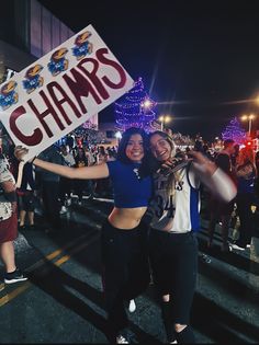 two women holding up a sign that says champs in front of a group of people