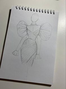 a drawing of a woman's dress on a piece of paper next to a clock