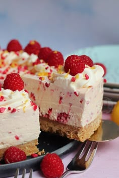 a cake with white frosting and raspberries is on a plate next to a fork