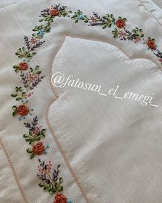 an embroidered white shirt with flowers and leaves on the front, along with a pink flowered border