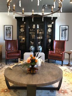 a living room filled with furniture and a chandelier hanging from the ceiling over a coffee table