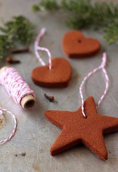 some brown and white ornaments on a table with twine, spools of thread and heart shaped cookies