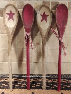 three wooden spoons with red and white stars on them, tied to a brick wall